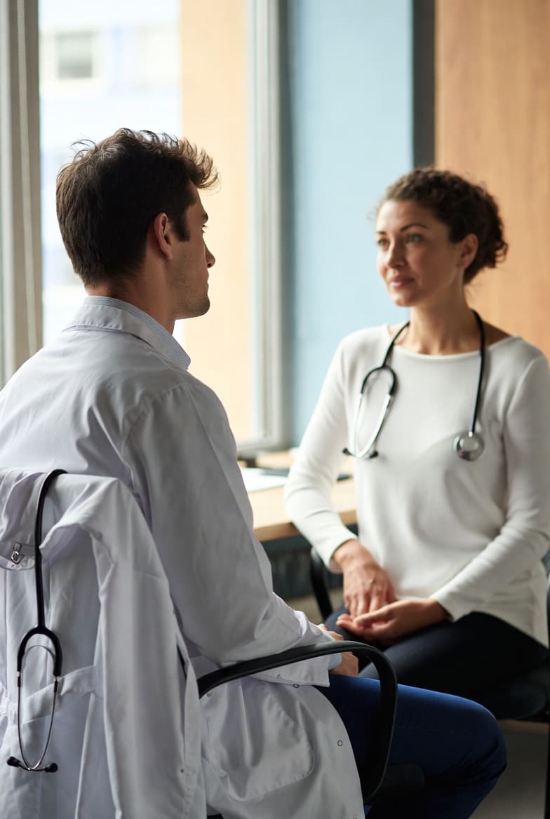 Physician coach speaking with a healthcare colleague in a professional setting
